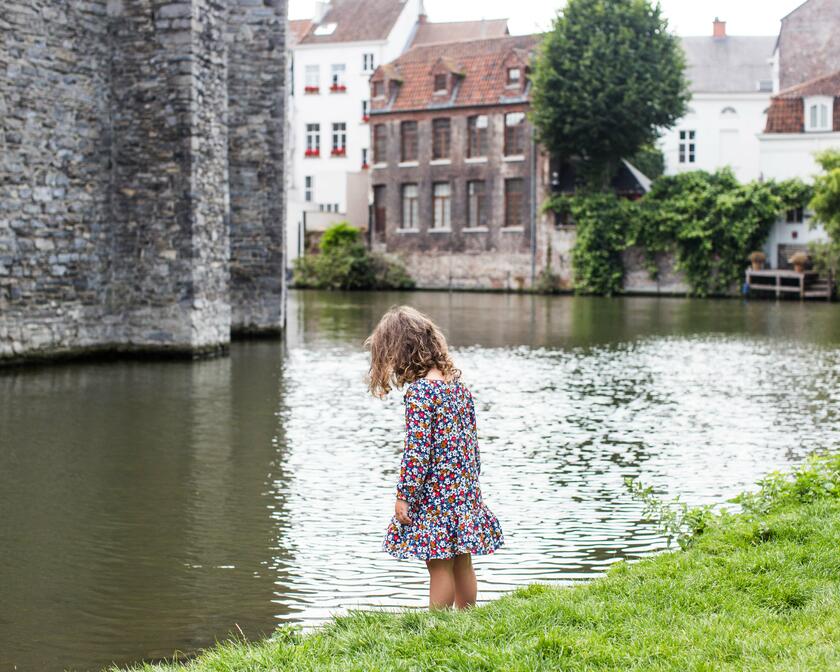 Klein meisje staat mijmerend aan de oever van de walgracht rond het Gravensteen