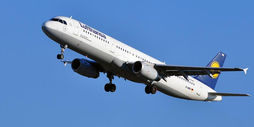 A Lufthansa-plane taking off into a clear blue sky.