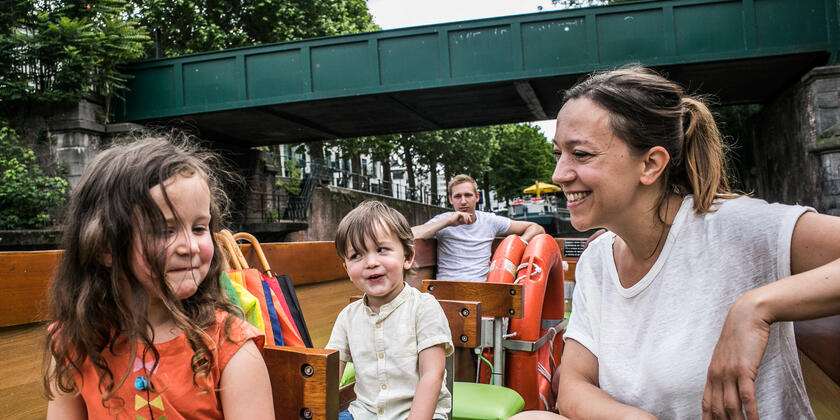 Une mère, une fille, un fils et un père se trouvent dans un bateau, naviguant dans le centre de Gand.