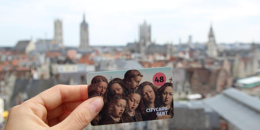 Une main avec un CityCard de la ville de Gand (72 heures) avec en arrière-plan la célèbre vue de la ville de Gent. (Depuis le toit du Château des Comtes)
