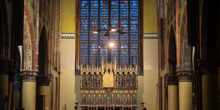 Eettafels in een kerksetting met op de achtergrond een middeleeuws orgel en een glas-in-loodraam.