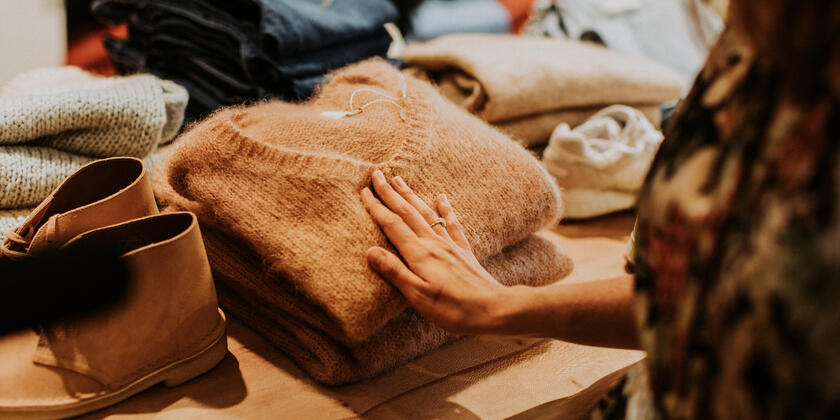 Persoon raakt een bruine wollen trui aan tijdens het shoppen in Gent