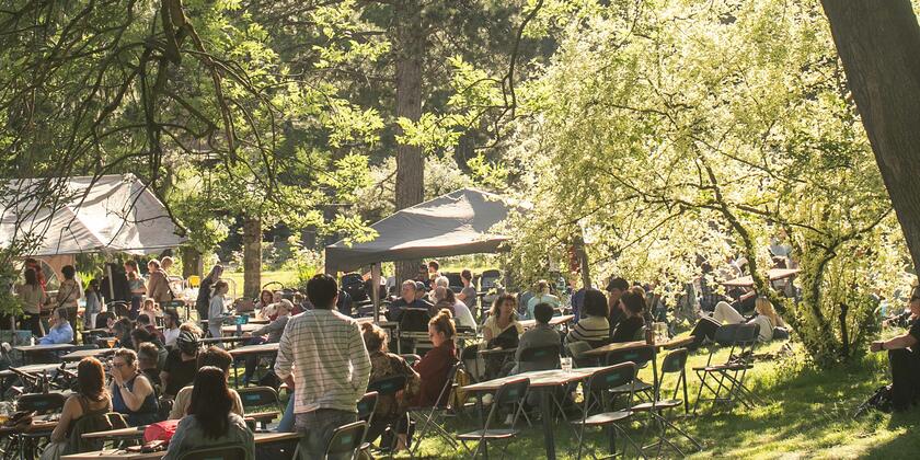 Mensen aan gezellige tafeltjes in bos tijdens het Citadellic festival in Gent