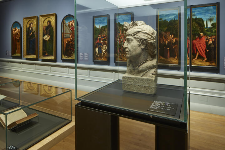 zaal met daarin schilderijen van het lam gods en een buste van van eyck