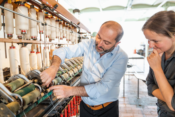 El hombre muestra el efecto de la máquina textil en el Museo de la Industria en Gante