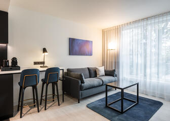 hotelkamer met blauwe en zwarte accenten, zetel, tafel, 2 barstoelen