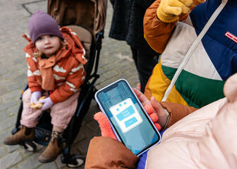 Gezin bekijkt hun score op de smartphone tijdens de wandelzoektocht van Draakje Fosfor