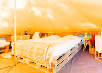 Espace de couchage à l'intérieur d'une tente glamping sur camping Urban Garden Blaarmeersen