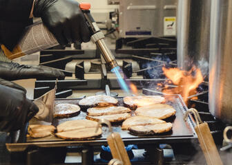 des tranches de viande sur le grill sont roussies à l’aide d’un brûleur à gaz