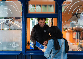 Fatina gibt ihre Bestellung an den Blauen Kiosk am Kouter in Gent weiter