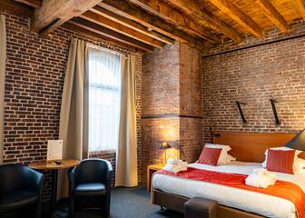 Deluxe kamer met opgemaakt dubbel bed en houten balken aan het plafond.