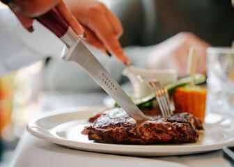 Persoon eet een steak in het Midtown Grill Restaurant