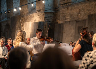 Scènes de Lauden 2023: un orchestre à cordes intime est entouré par le public présent dans le réfectoire historique de l'abbaye de Saint-Bavon