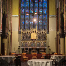 Eettafels in een kerksetting met op de achtergrond een middeleeuws orgel en een glas-in-loodraam.